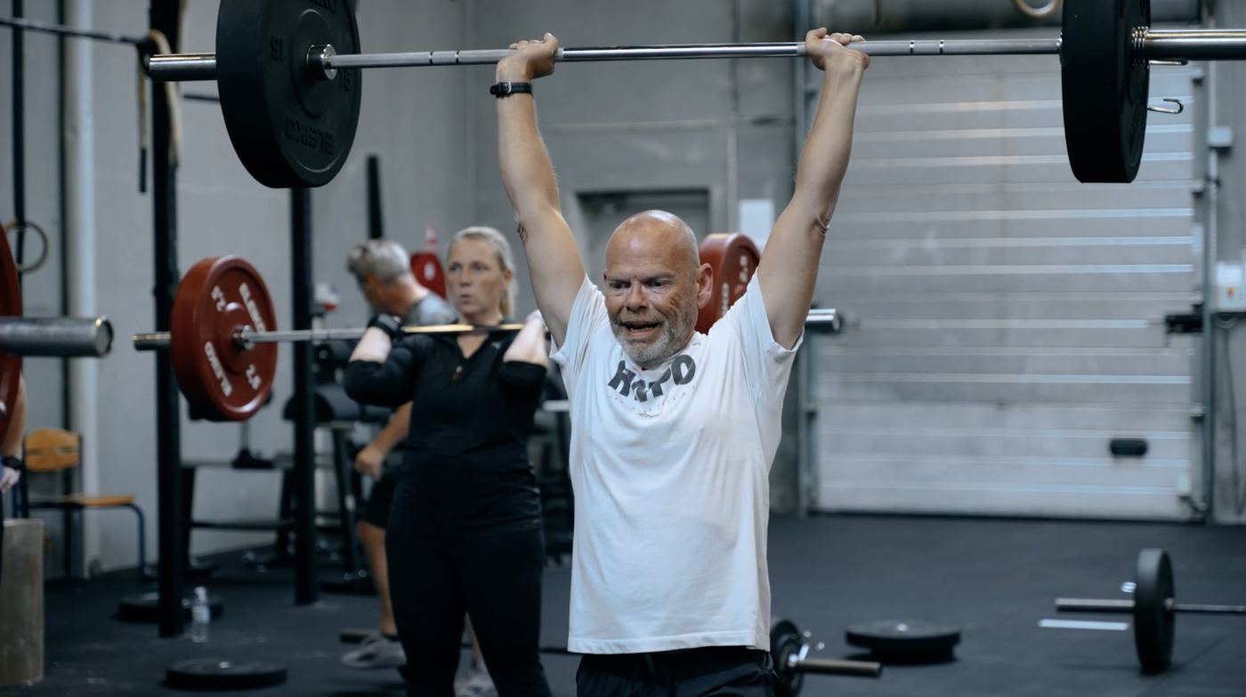 Medlem løfter vægtstang over hovedet